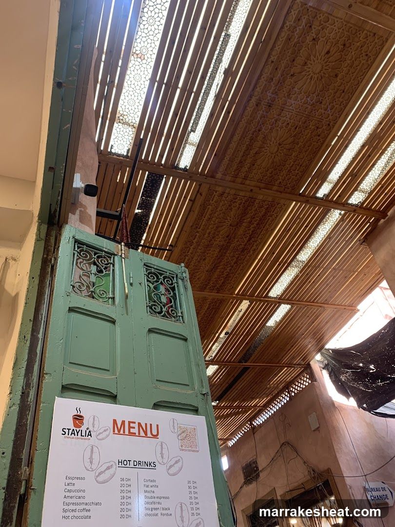 A photo showing an interior space with a menu board attached to a green door frame. The ceiling features wooden slats and decorative panels, allowing natural light to filter through.