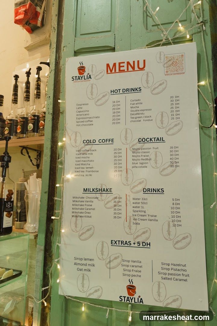 A printed menu board mounted on a green wooden door frame, featuring coffee and cocktail options with prices in DH.